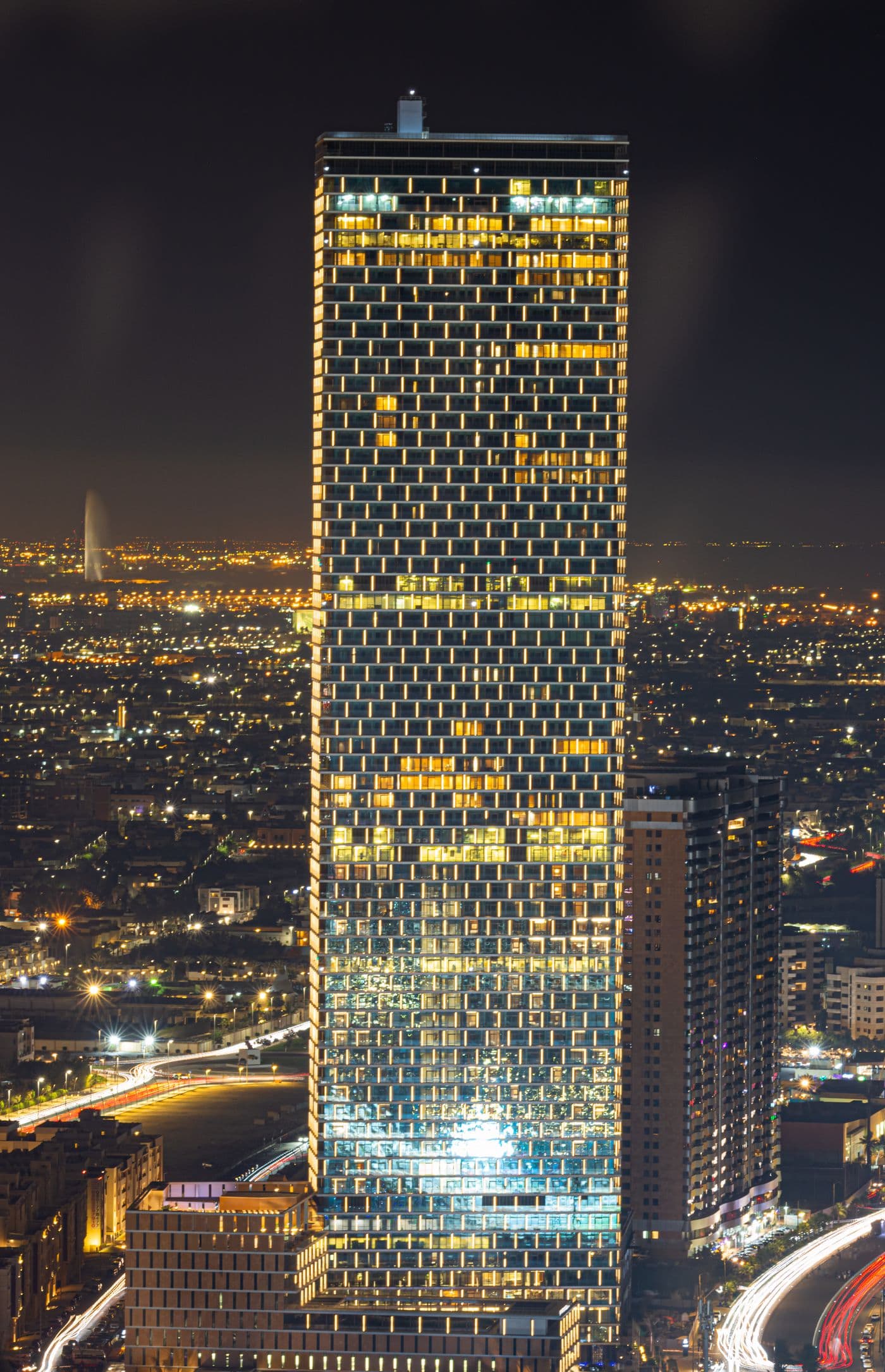 Illuminated Saudi commercial tower in a modern business district at night